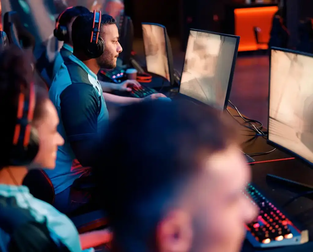 Meerdere gamers spelen samen achter computers in een esportsclub. De spelers dragen headsets en communiceren terwijl ze deelnemen aan een wedstrijd.