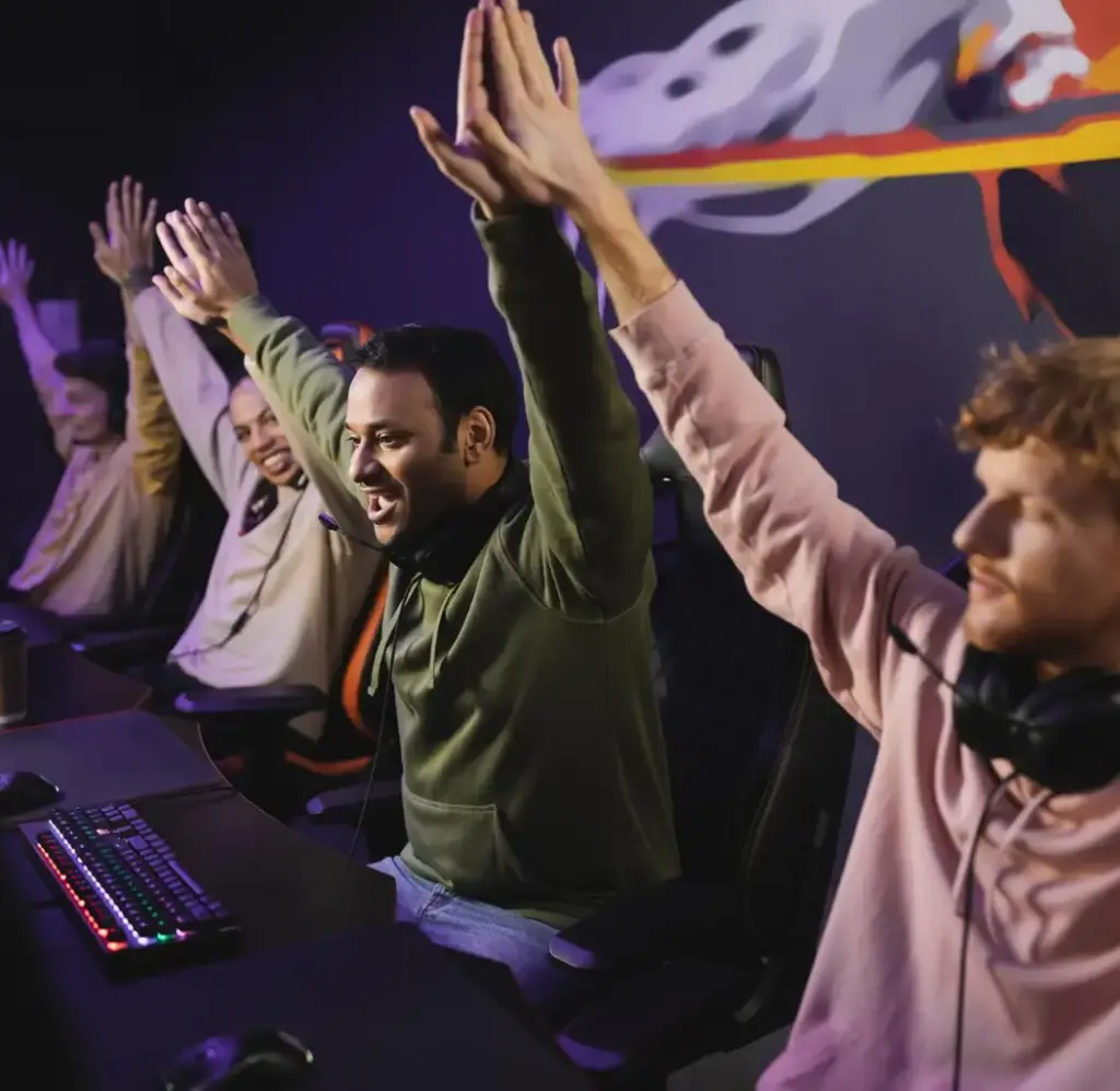 Een team van gamers viert een overwinning terwijl ze achter hun gamingstations zitten. De spelers steken hun handen omhoog na een succesvolle wedstrijd.