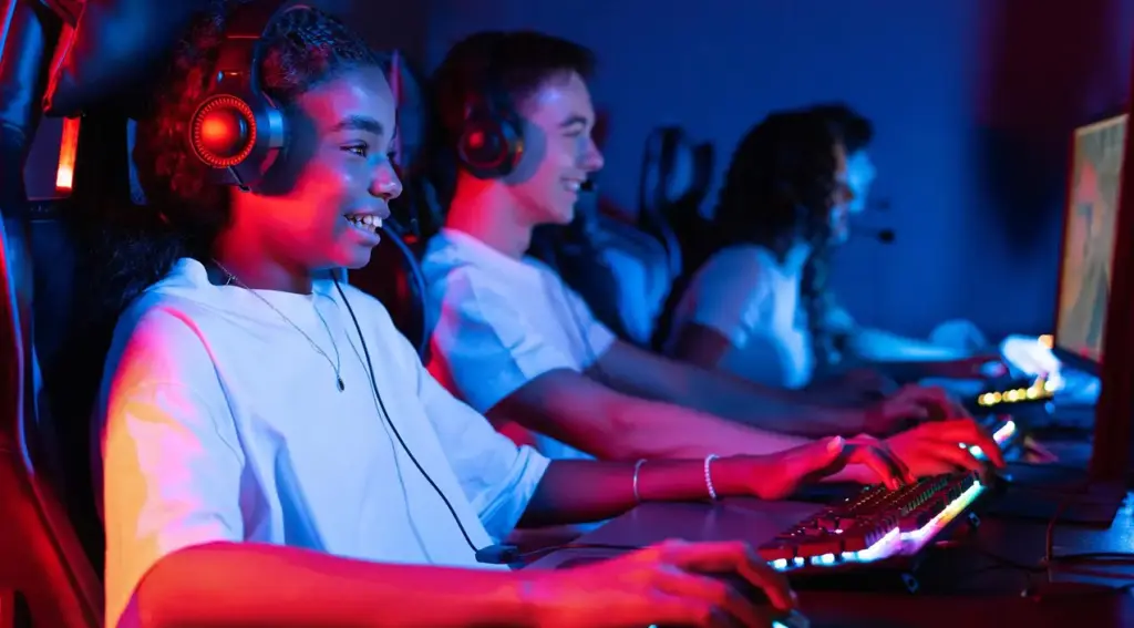 Jonge gamers spelen samen videogames achter verlichte gamingcomputers. De sfeer in de esportsruimte is energiek en kleurrijk.